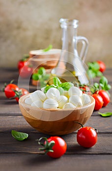 Italian food ingredients Ã¢â¬â mozzarella, tomatoes, basil and olive oil on rustic wooden table.